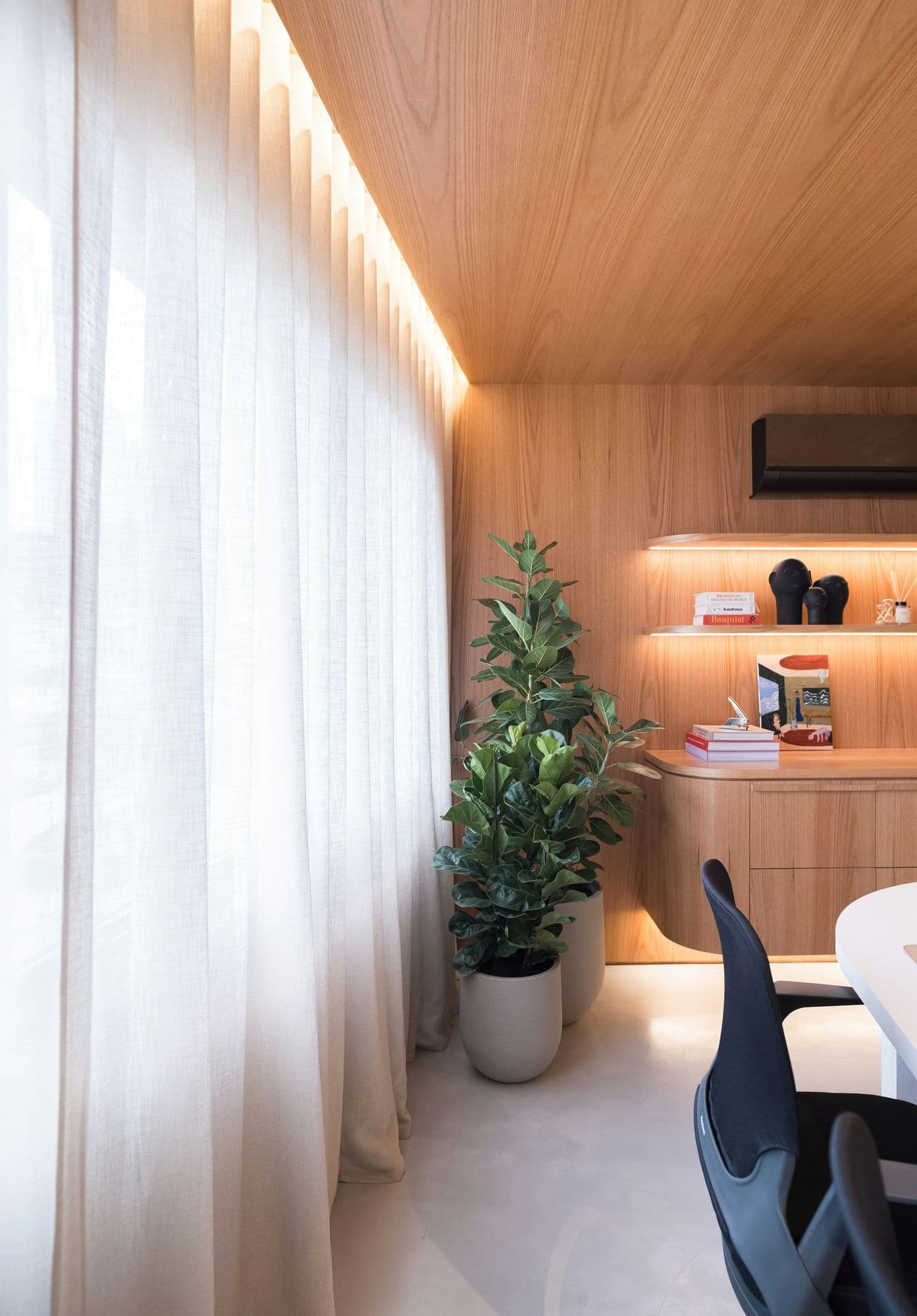 Home office compacto com bancada e nichos iluminados em madeira clara