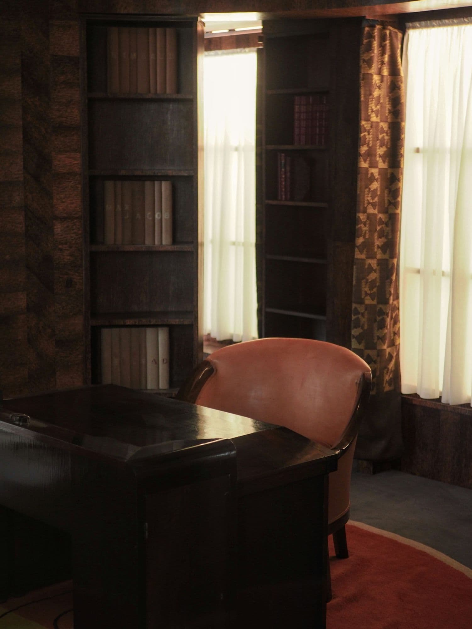 Sala com estante de madeira escura, livros e poltrona de leitura
